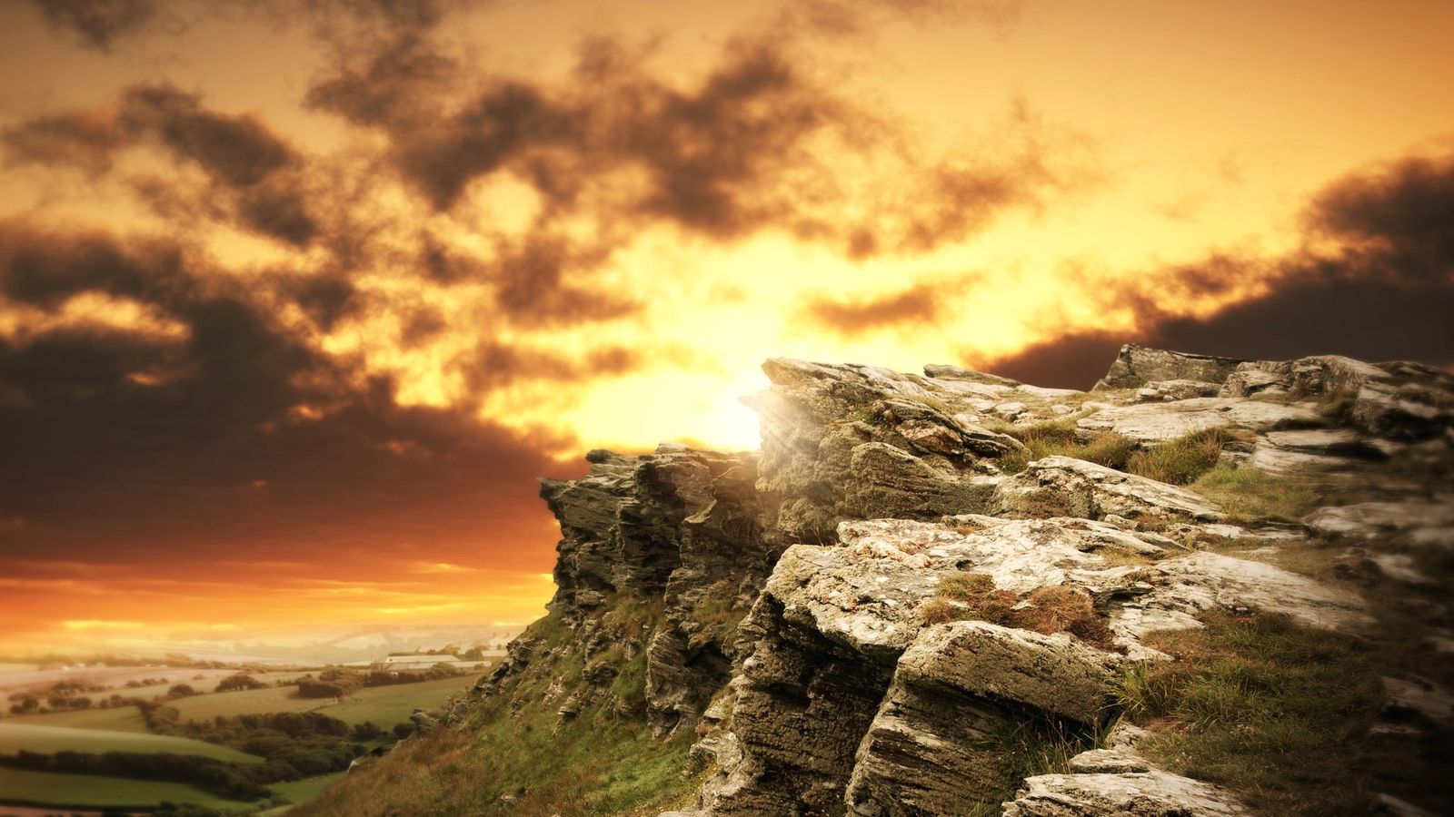 Low sun breaking through cloud over a weathered rock outcrop
