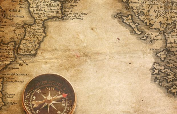 An old printed map with a compass lying at its edge