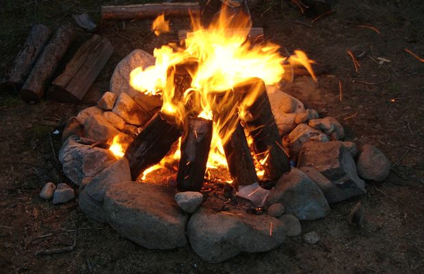 A campfire burning inside a ring of stones at night