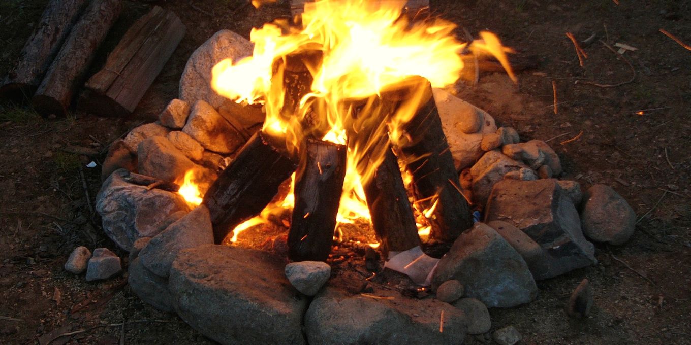A campfire burning inside a ring of stones at night