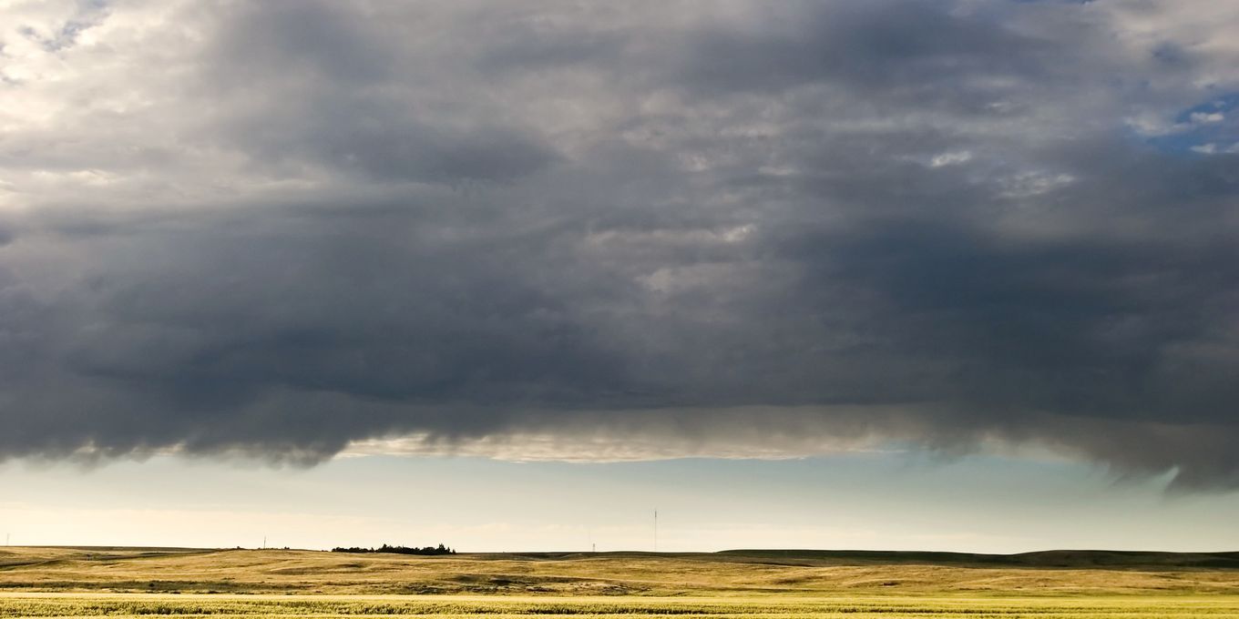 A storm front building over a flat, open plain