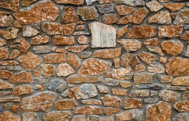 Close view of a dry-laid wall of reddish and gray stones