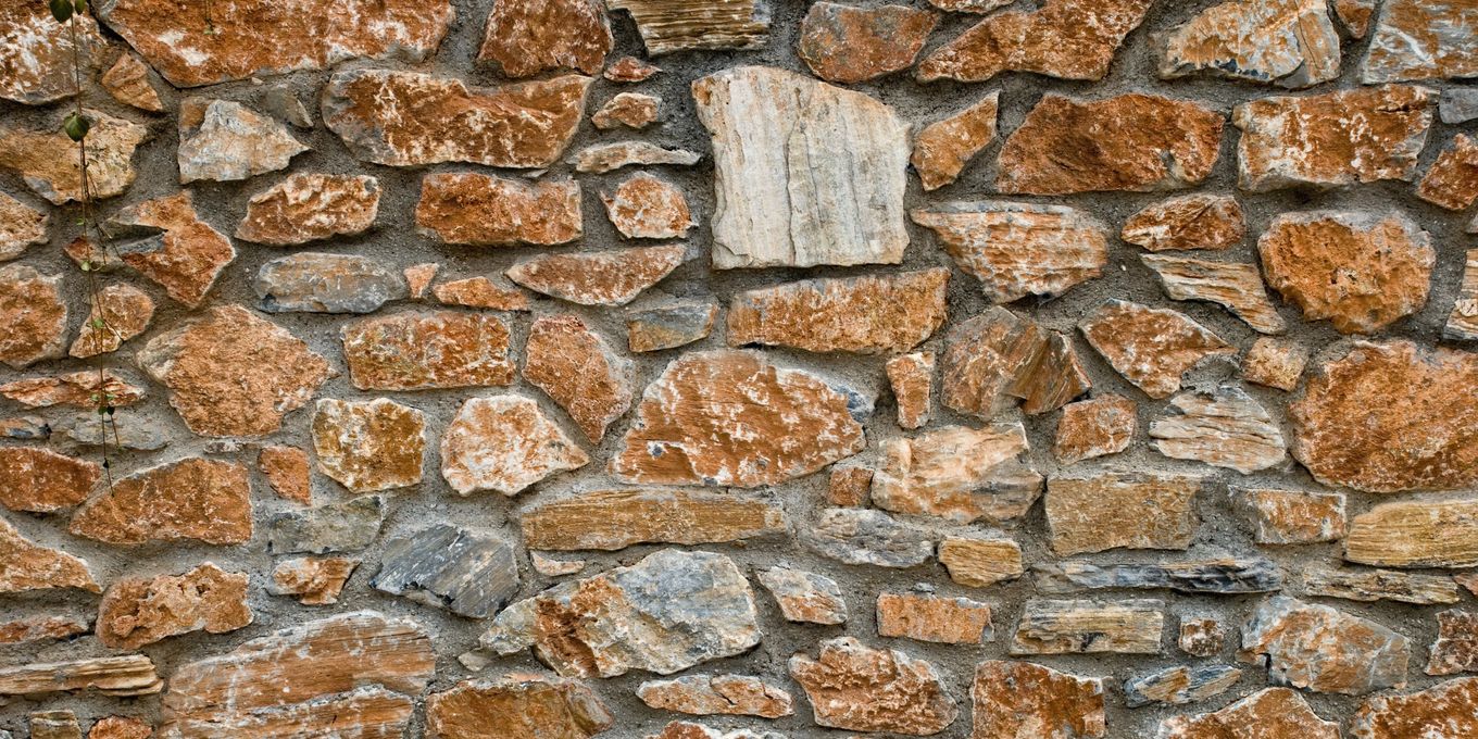 Close view of a dry-laid wall of reddish and gray stones