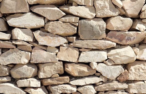 A wall of pale, rough-cut stones laid without mortar